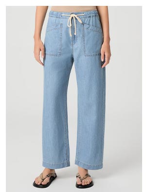 A woman's legs wearing a light blue wash denim pant and snakeskin effect leather sandals.