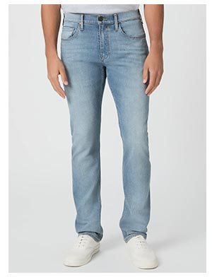 A man's legs wearing light vintage wash blue jeans paired with white leather sneakers.