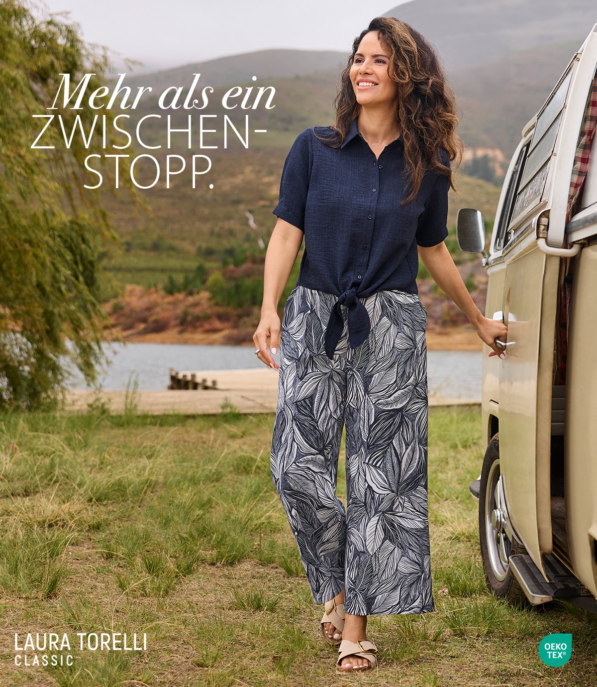Frauenmodel trägt kurzärmlige dunkelblaue Bluse, gemusterte weite Hose in Blau und Weiß, Sandalen, Vorderansicht