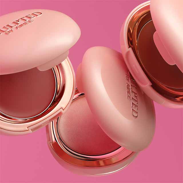 Three round, pink compact cases of blush open, displayed against a pink background.