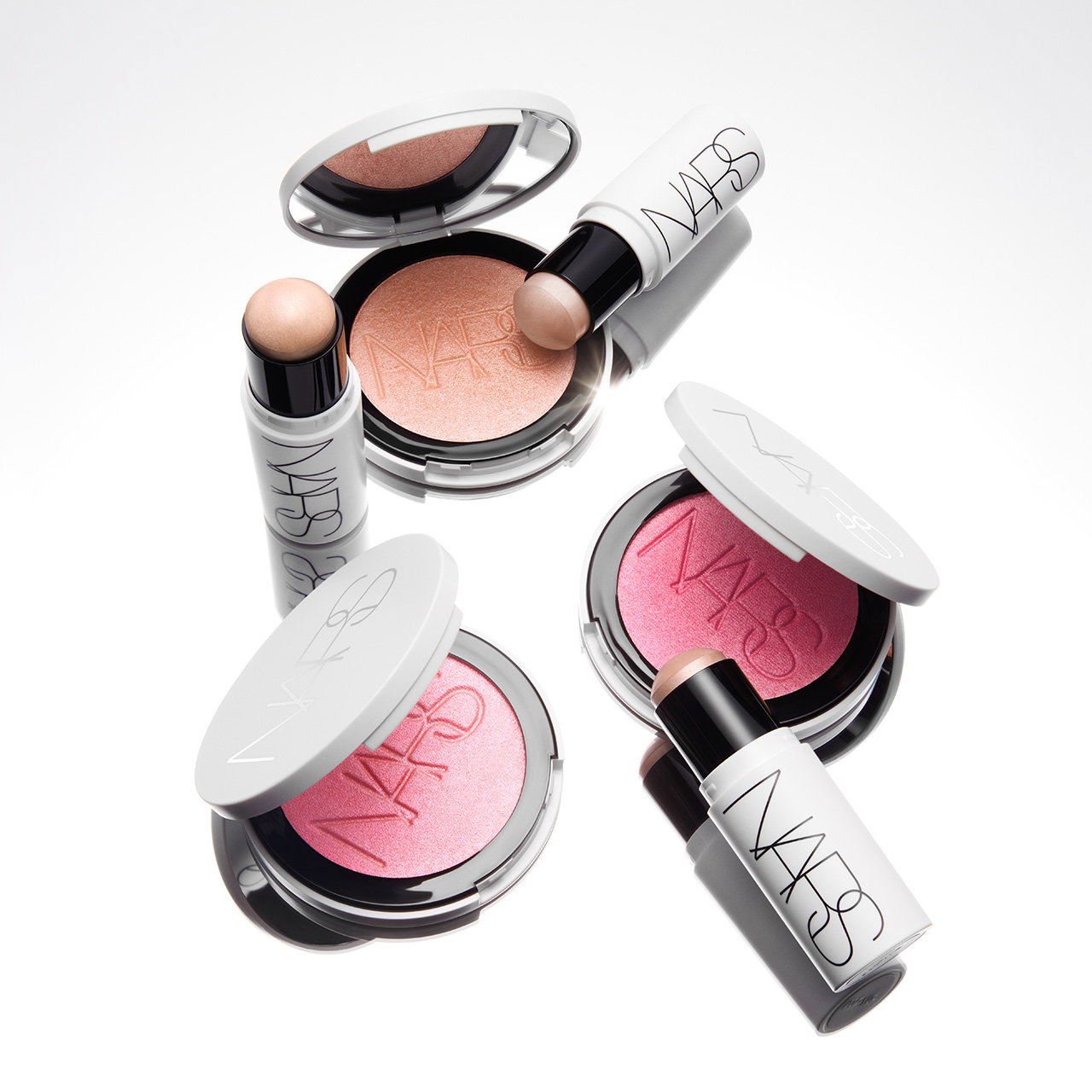 Three NARS makeup products with open compacts showing peach and pink shades, and two lipstick tubes on a white background.