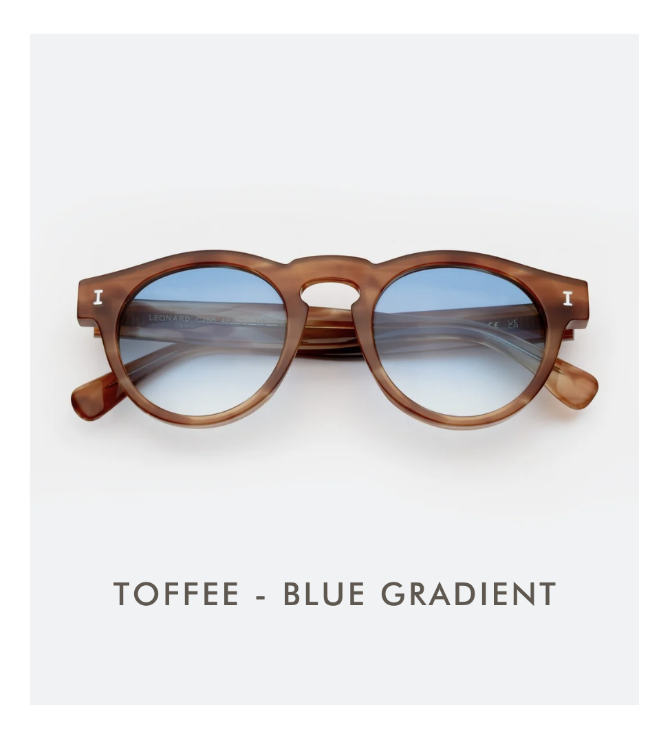 A studio product shot of the Leonard sunglasses in Toffee with Blue Gradient lenses. The frames are a translucent warm amber, and the lenses fade from a vibrant blue to clear.