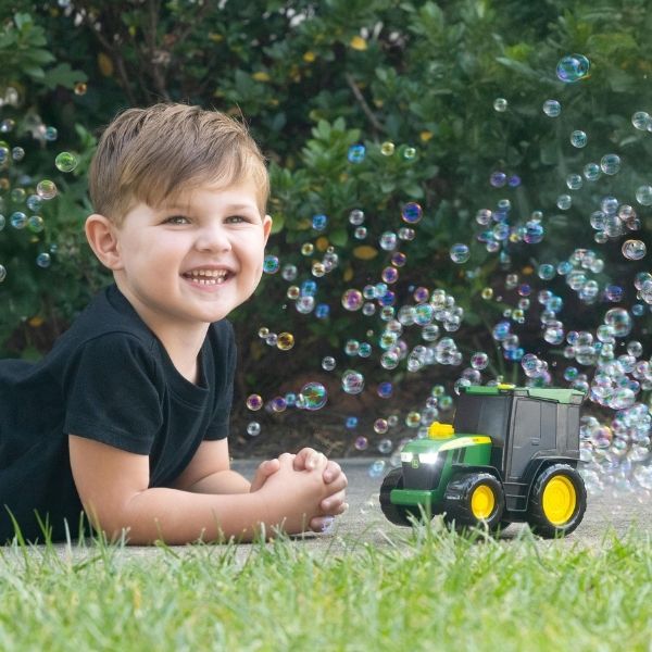 Child playing with toy tractor blowing bubbles