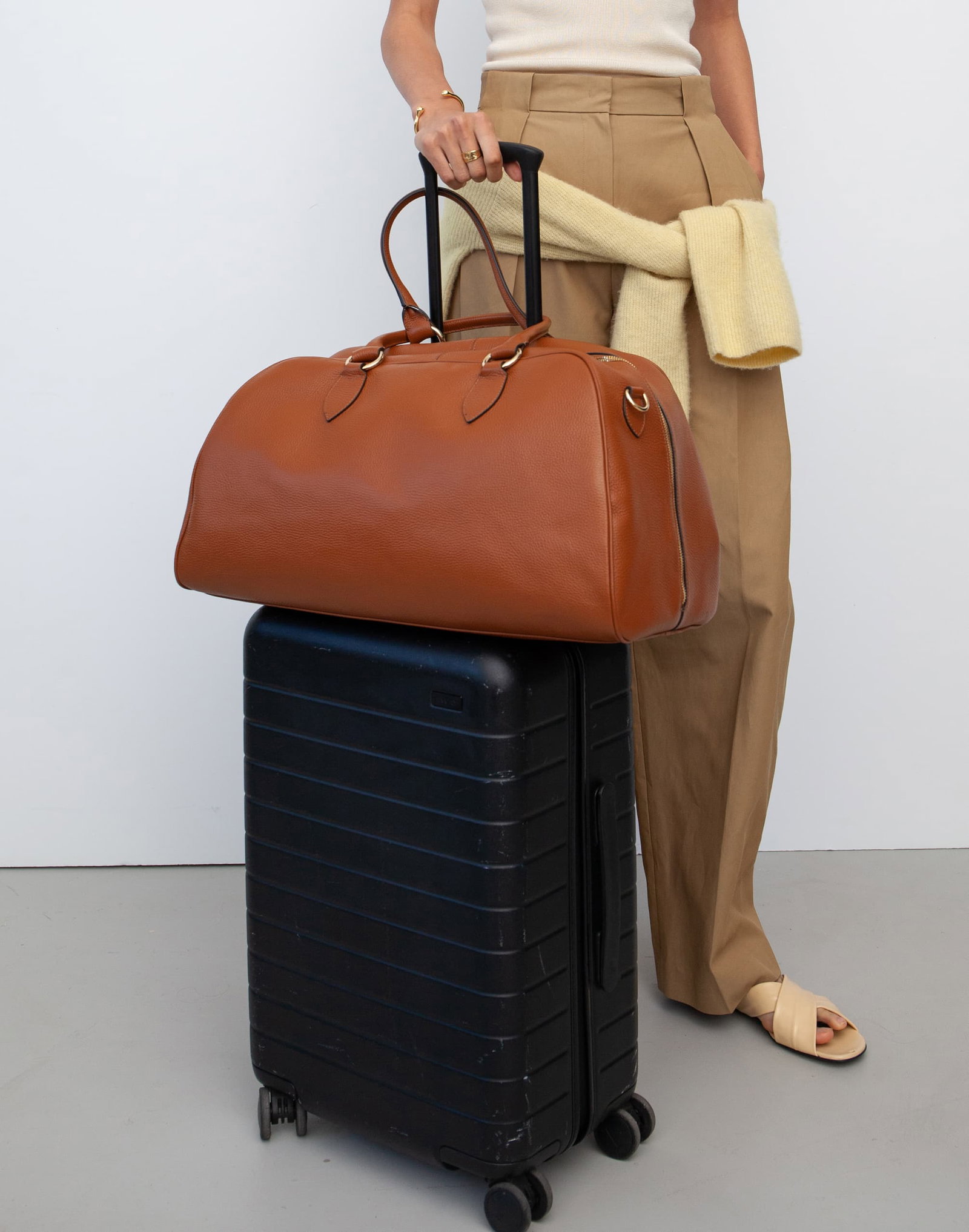 The HYER GOODS La VIa weekender in Cognac, atop a carryon rollerboard