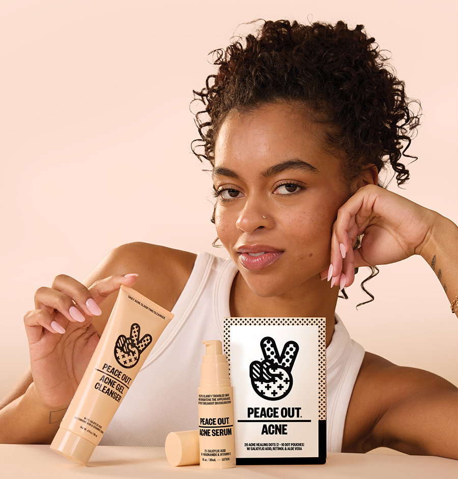 A woman holds up Acne Gel Cleanser next to Acne Serum and Acne Healing Dots