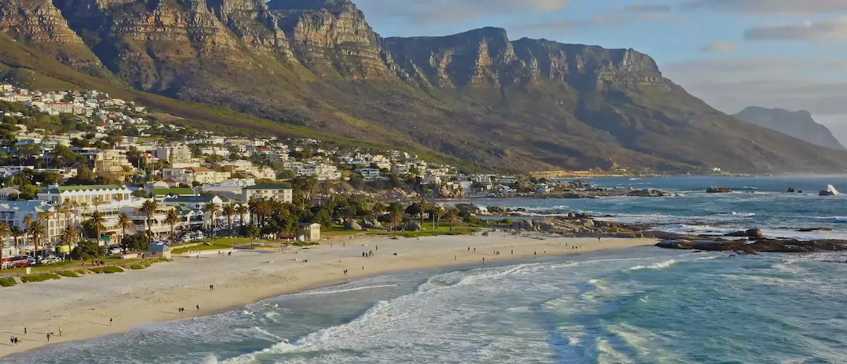 Blick auf Strand, Tafelberg und Häuser von Kapstadt an einem sonnigen Tag.