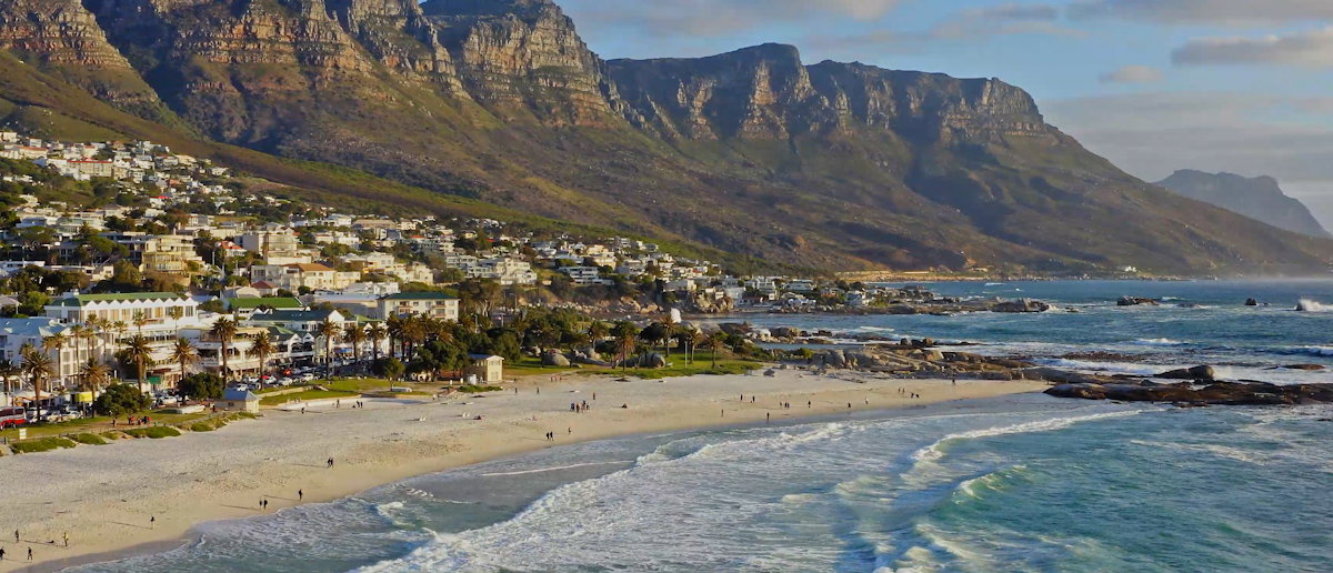 Blick auf Strand, Tafelberg und Häuser von Kapstadt an einem sonnigen Tag.