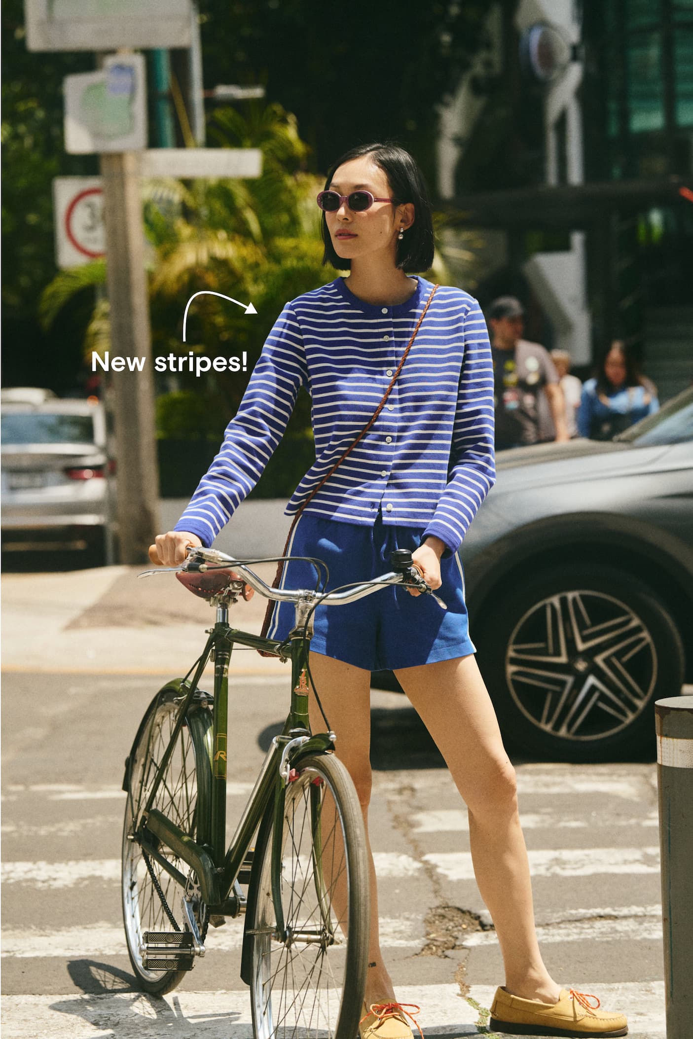woman in blue and white striped top with blue shorts holding bike