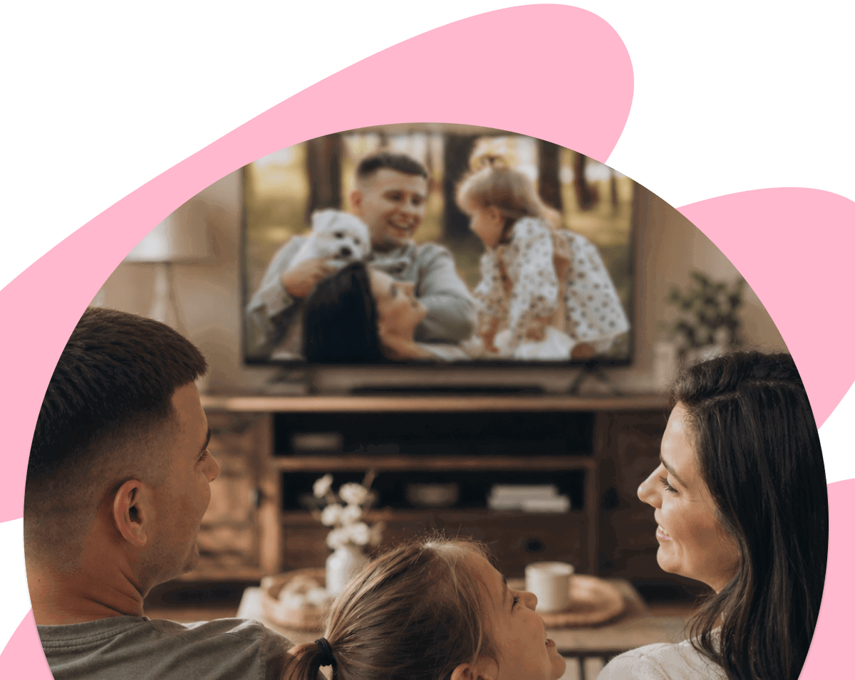Family watching a Mother’s Day video gift together on TV, smiling as they enjoy favorite photos and memories at home.