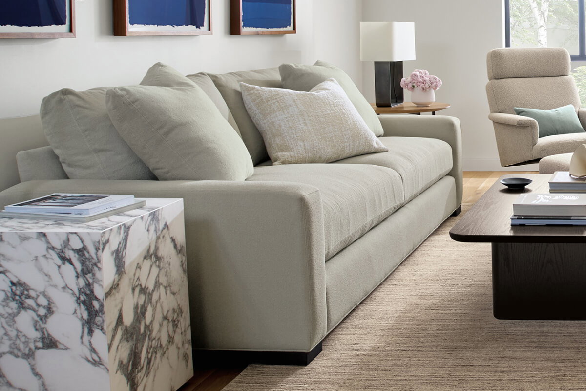 Metro sofa in light grey upholstery, shown with marble side table and dark wood coffee table in living room.