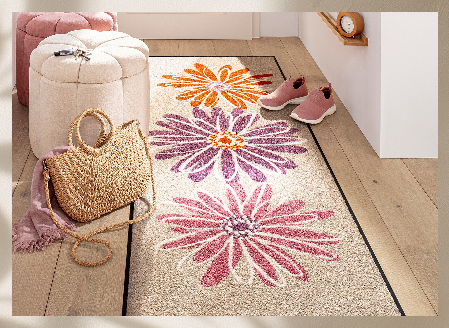 Heller Flur mit Läufer, der große Blumen in Orange, Lila und Pink zeigt. Daneben Korbtasche, rosa Schuhe und Sitzhocker.