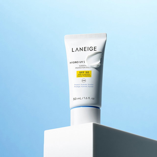 A tube of Laneige Hydro UV Defense SPF 50 sunscreen on a light blue background.
