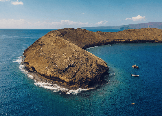 Aerial view of a volcanic crater surrounded by turquoise ocean.