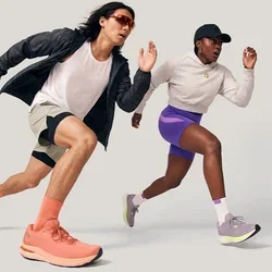 Dos corredores, un hombre y una mujer, corriendo a toda velocidad hacia adelante con ropa deportiva y zapatillas deportivas sobre un fondo claro y liso.