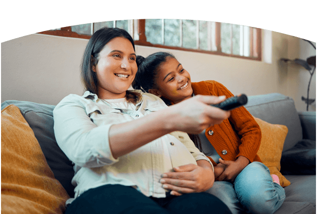 Mother and daughter on the couch watching TV together on