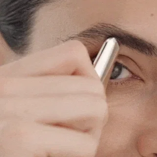 Eye close-up of a person scooping and gliding outward along the brow and undereye with the Rejuvenating Eye Tool.