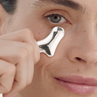 Face close-up of a person gliding the Rejuvenating Eye Tool under the eye.