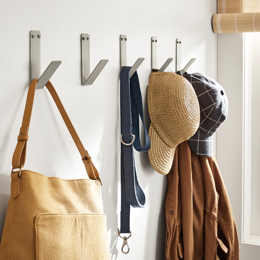 Crew wall hooks in a row on the wall, used to hang a bag, leash, hats, and jacket.