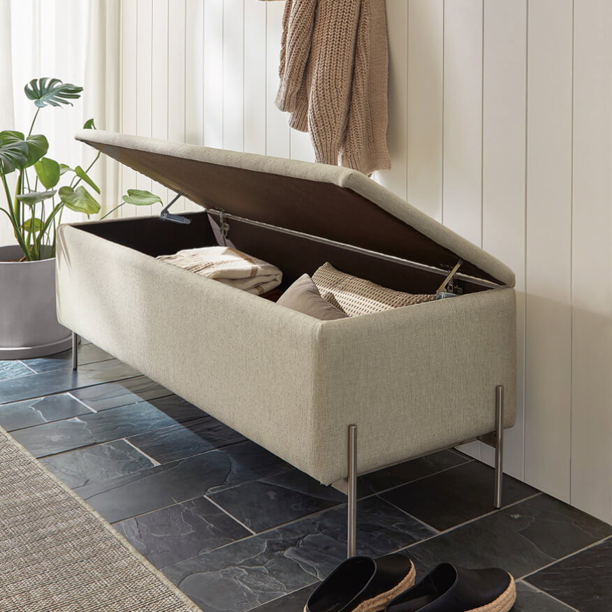 Paxton bench with hinged upholstered top lifted to show interior storage, styled in entryway with a plant.