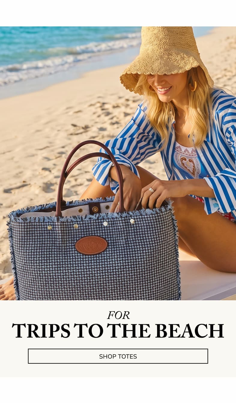For Trips To The Beach. CTA: Shop Totes. Model on beach with Olympia tote in blueberry. 
