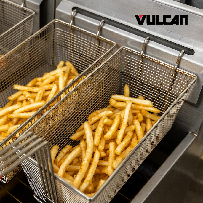 Vulcan commercial fryer with wire baskets holding freshly cooked French fries inside a stainless steel fryer.