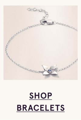 A white metal flower bracelet with a blue sapphire in its center. Click here to shop bracelets