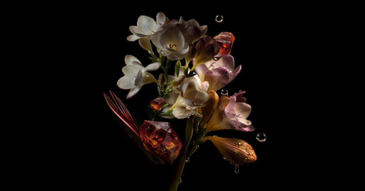 Fiori bianchi di gelsomino e freesia tra gocce d'acqua e cristalli ambrati su sfondo nero