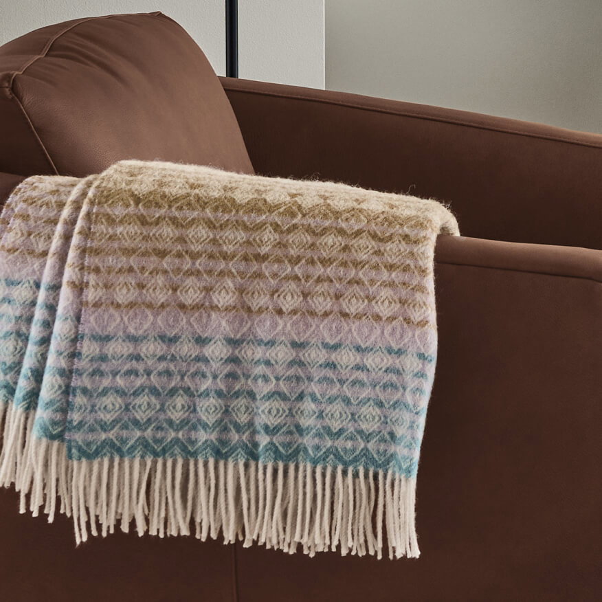 Wycliff throw draped over a brown chair, featuring woven texture and fringe edge.
