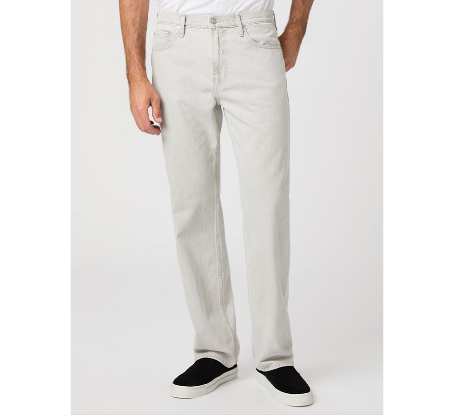 Man wearing a pair of light grey relaxed straight-leg jeans with a white tee and black sneakers in front of a grey backdrop.