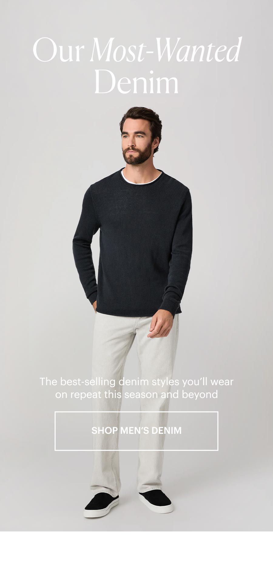 Our Most-Wanted Denim: The best-selling denim styles you'll wear on repeat this season and beyond. Shop men's denim. Featuring a an wearing a black sweater over a white tee with light grey straight-leg jeans and black sneakers in front of a grey backdrop.