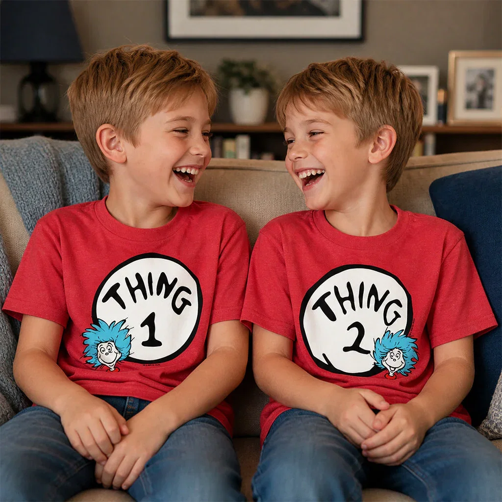Two young boys laughing on a couch wearing matching red Thing 1 and Thing 2 graphic t-shirts.