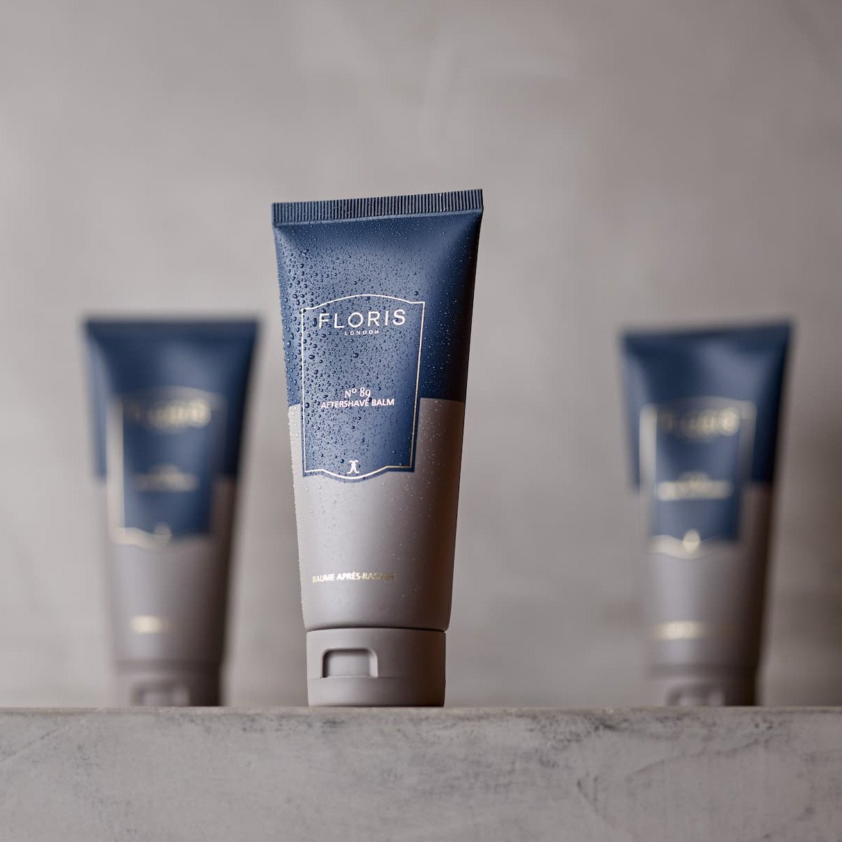 Floris shaving cream is pictured against a grey background with two bottles blurred in the background