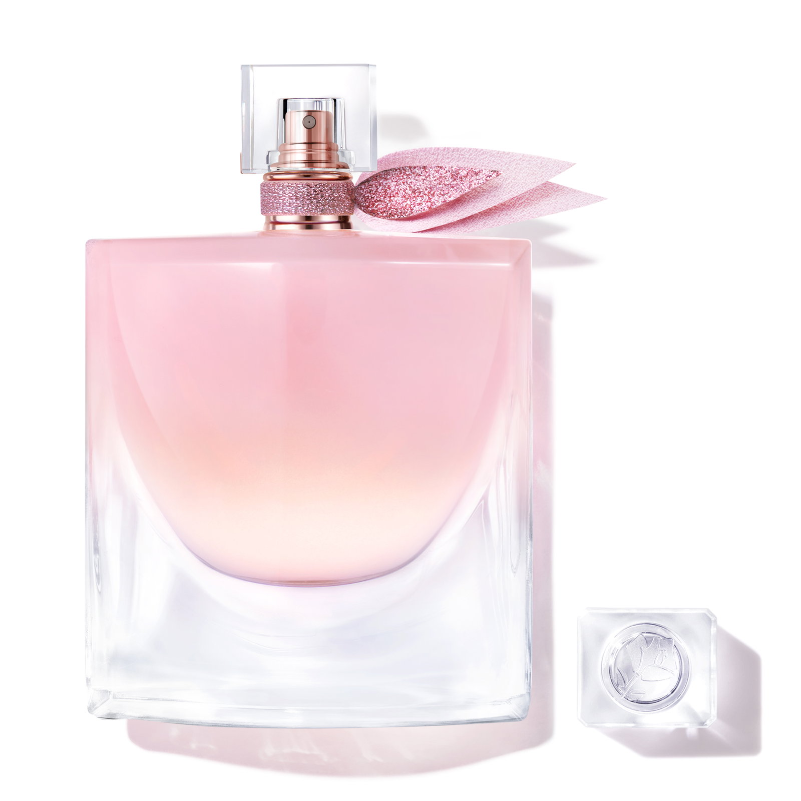 Flacone icona La Vie Est Belle in vetro sfumato rosa opalescente, decorato con ali in tulle glitterato rosa antico, accompagnato dalla mini versione abbinata. Fondo bianco.