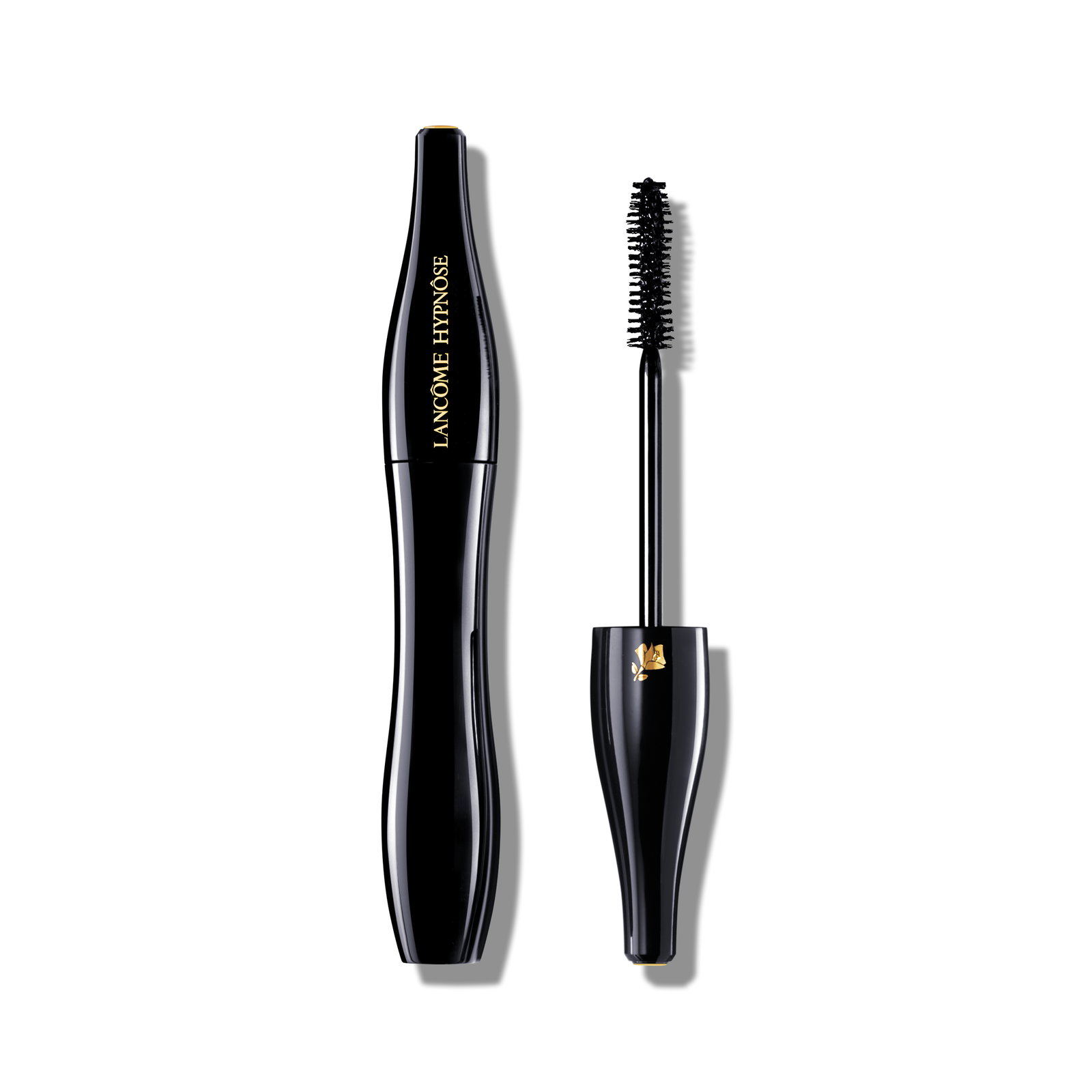 Flacone mascara nero dalla silhouette scultorea con scritta dorata Lancôme Hypnôse e pennello separato con dettaglio a rosa dorata. Fondo bianco.