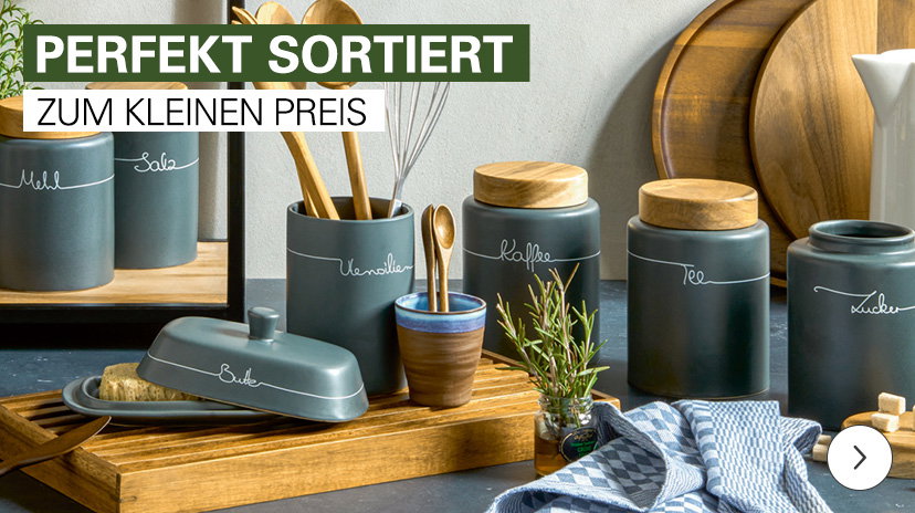Verschiedene Vorratsdosen und Küchenutensilien aus dunkelgrauer Keramik mit Holzdeckeln und weißer Beschriftung, arrangiert auf Holzbrettern. Die Grafik enthält die Textfelder ‚PERFEKT SORTIERT‘ und ‚ZUM KLEINEN PREIS‘.