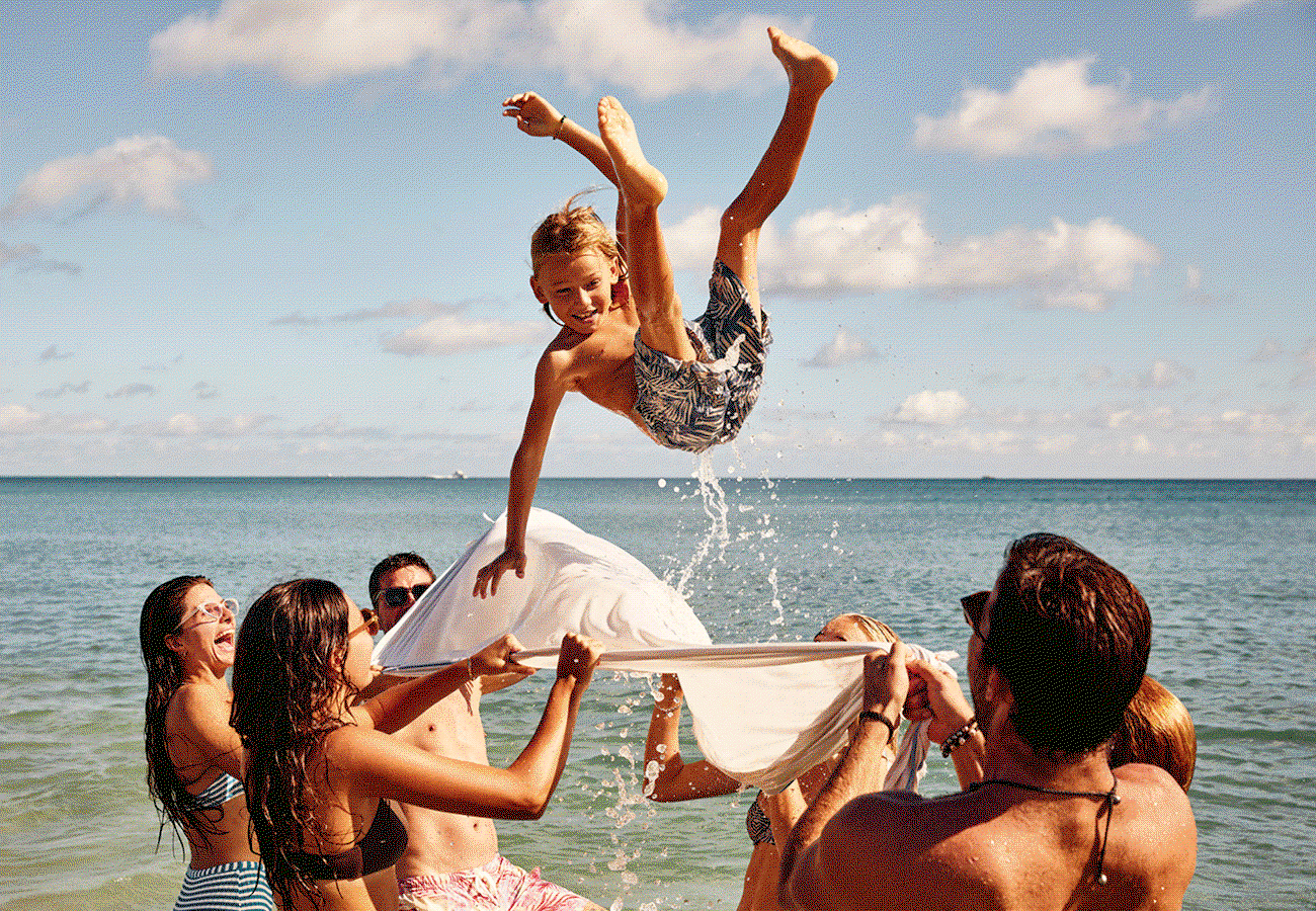 Hero GIF featuring 4 frames: 1) A group playfully tossing a boy into the air above shallow seawater with a towel. 2) Aerial view of a palm-lined resort swimming pool. 3) A woman riding a bicycle along a palm-lined path. 4) A resort with red clay roof tiles, featuring its pool, terrace, and lush outdoor space.