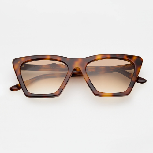 A studio product shot of the Lisbon sunglasses in Havana. The frames feature a bold, angular cat-eye silhouette in a dark amber tortoise shell pattern. The lenses are a warm brown gradient that fades to a light tan.