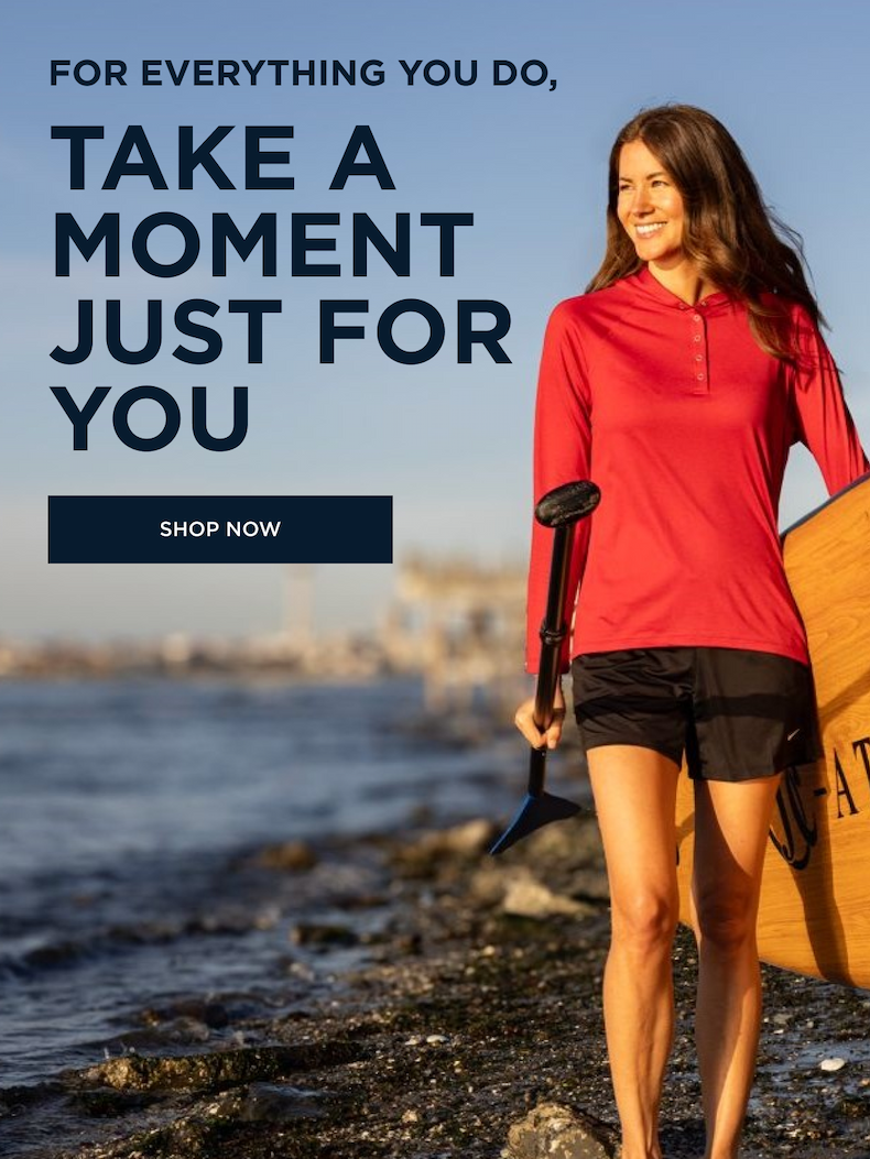 Smiling woman walking on the beach with a paddle board and oar | Shop Now