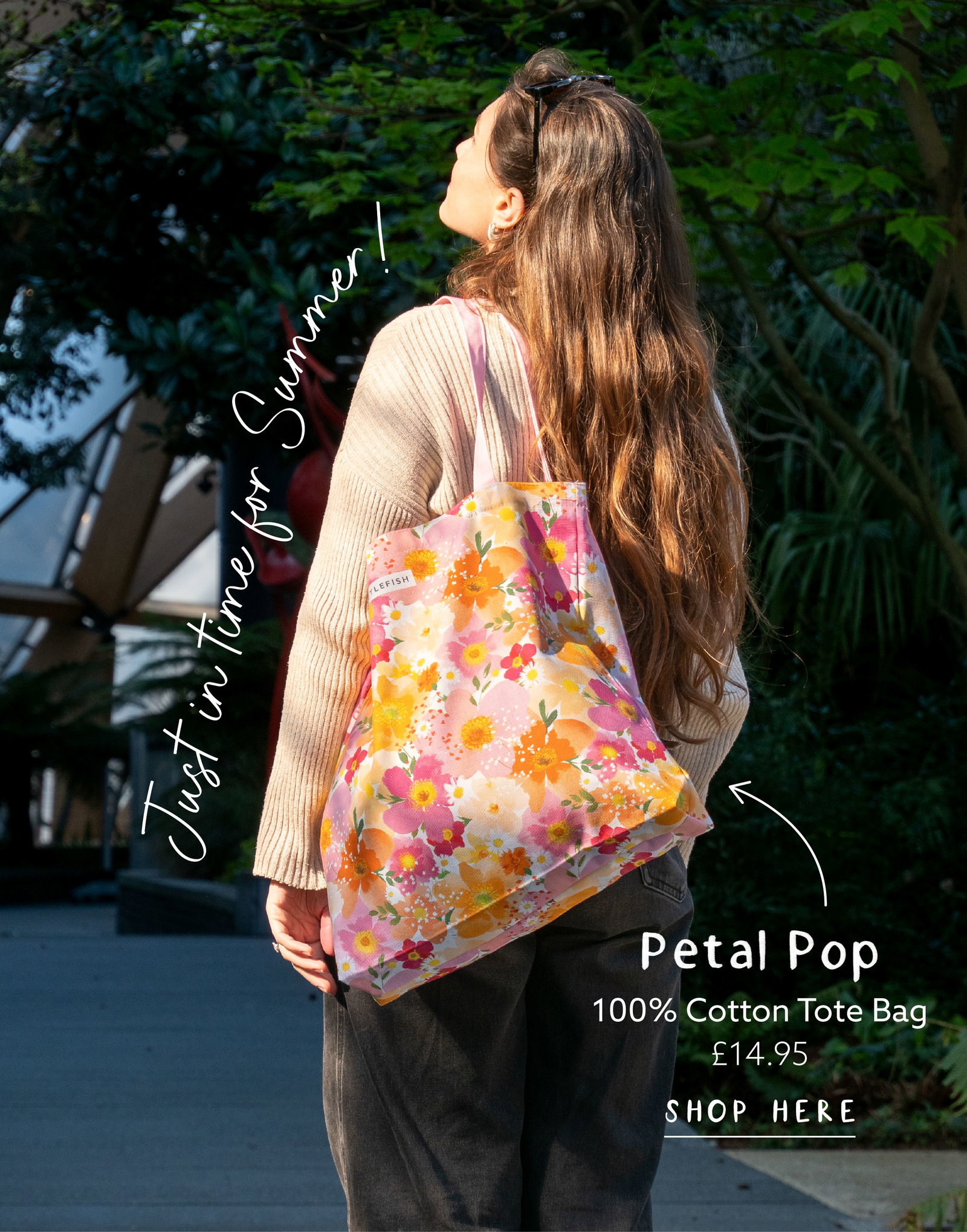 Model carrying the Petal Pop cotton tote bag outdoors in the sunshine. Soft floral print tote bag in pink, peach and orange tones styled for summer days and everyday shopping.