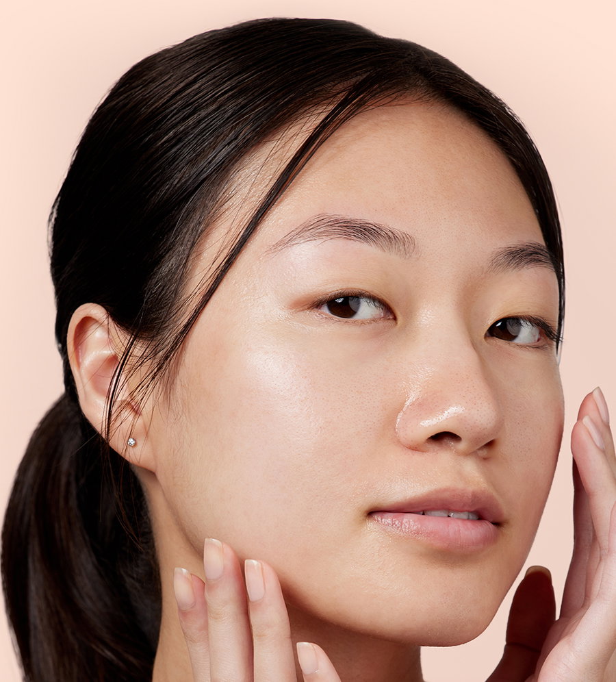 A woman looks directly into the camera with a fresh, dewy face.