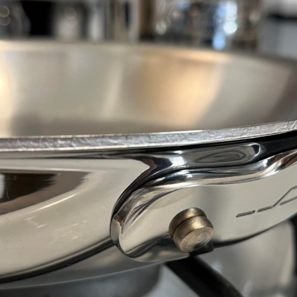 Image: An ordinary clad cookware is shown with a close up of an exposed aluminum layer. The edge is rough and susceptible to delamination.