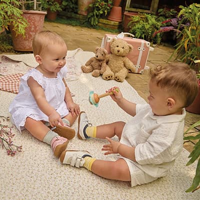 Two young children playing outside on a blanket