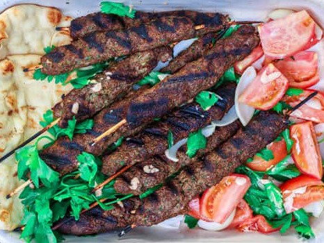 Kofta kebabs with pita and tomatoes on a platter.