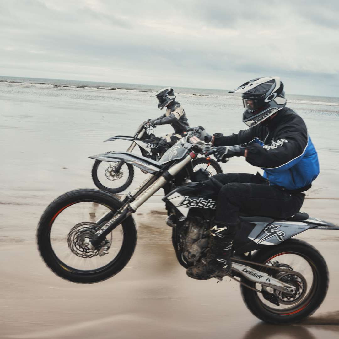 Models riding branded motorcross bikes across a welsh beach in Represent x Belstaff