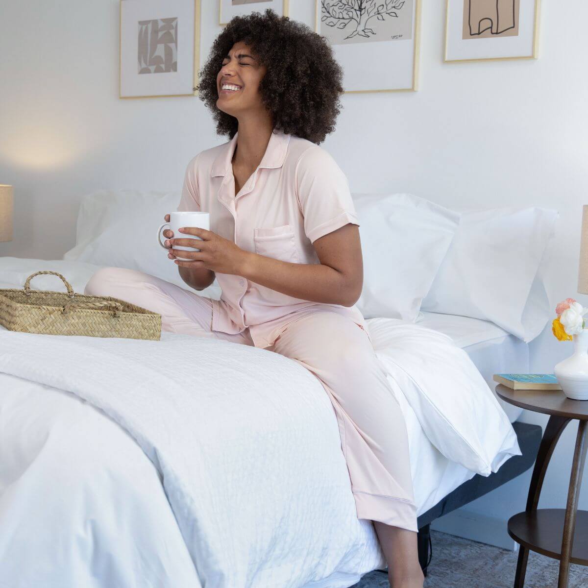 A woman holds a cup of coffee in bed