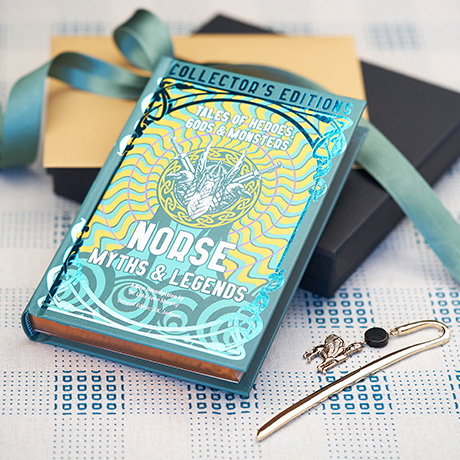 Norse Myths and Legends hardback book on a gift box with ribbon next to a metal Assyrian winged bull bookmark. - Shop Books.