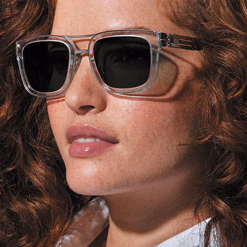 Woman with curly hair wearing clear frames with Transitions XTRActive lenses