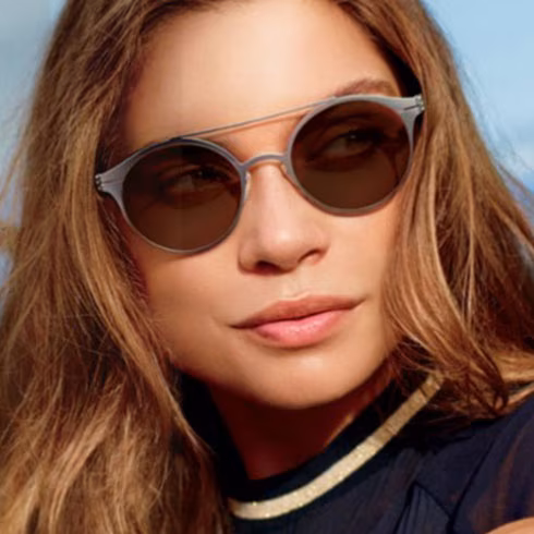 Woman with long hair wearing round, light frames with Transitions Drivewear lenses