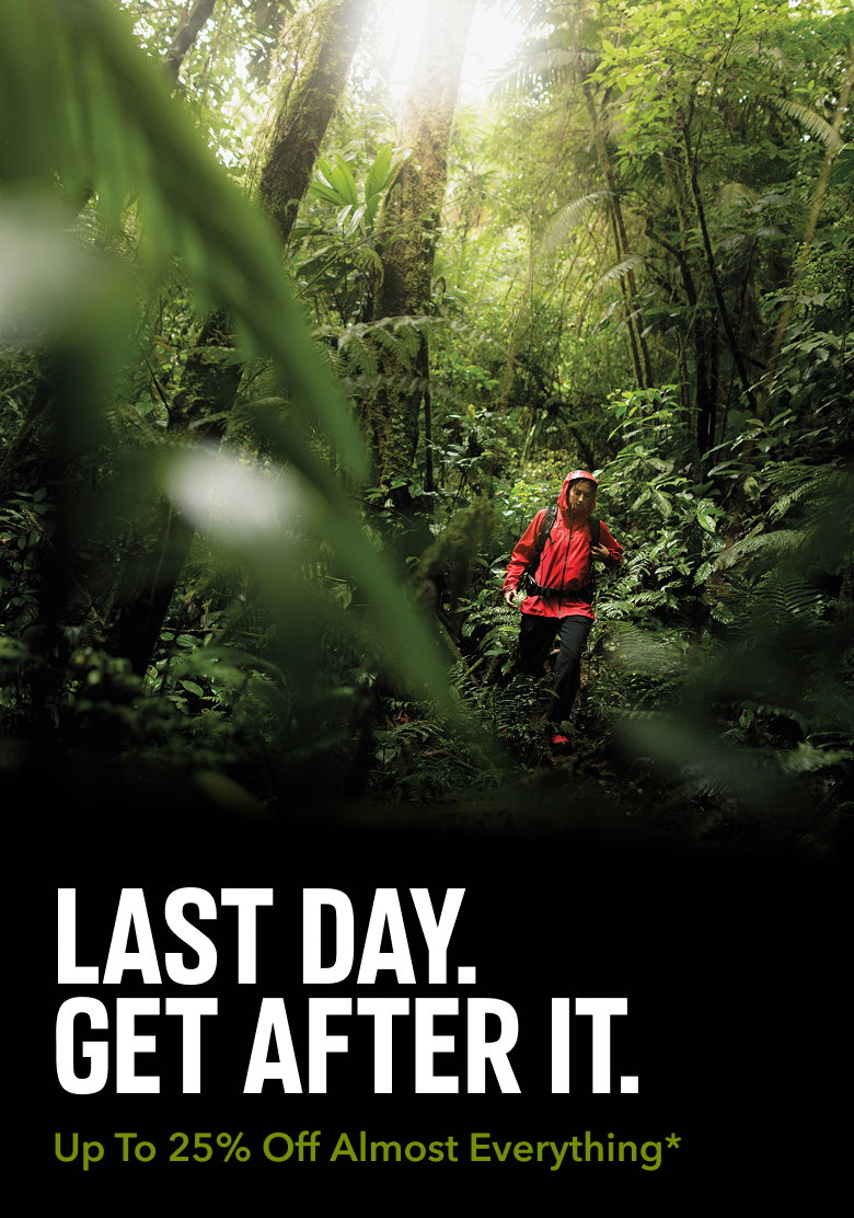 A hiker in a dense forest, wearing a bright red rain jacket and black pants with text: LAST DAY. GET AFTER IT. Up To 25% Off Almost Everything*