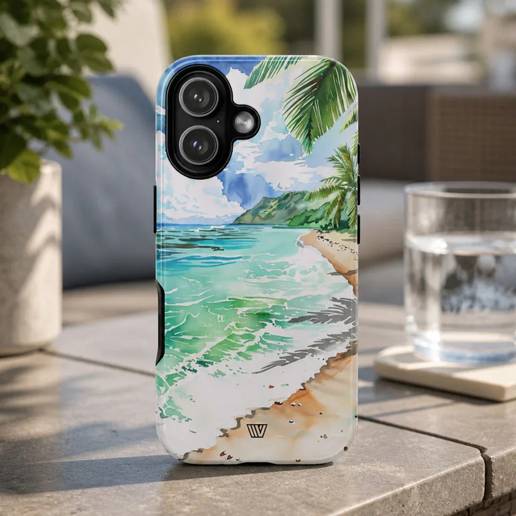 Tropical beach phone case with ocean, palm trees, and sandy shore design displayed outdoors on a patio table.
